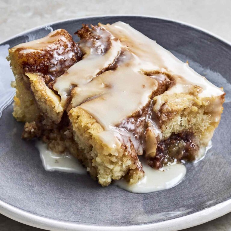 cinnamon roll cake with thick vanilla glaze dripping down the sides
