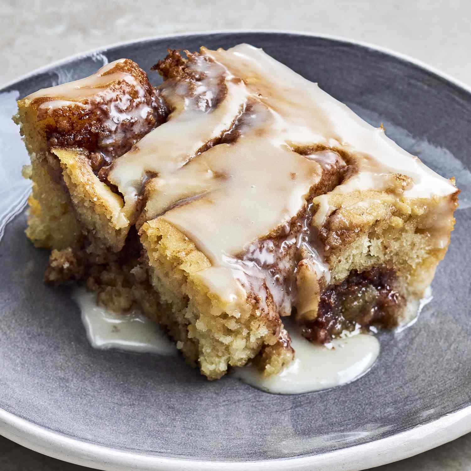 cinnamon roll cake with thick vanilla glaze dripping down the sides